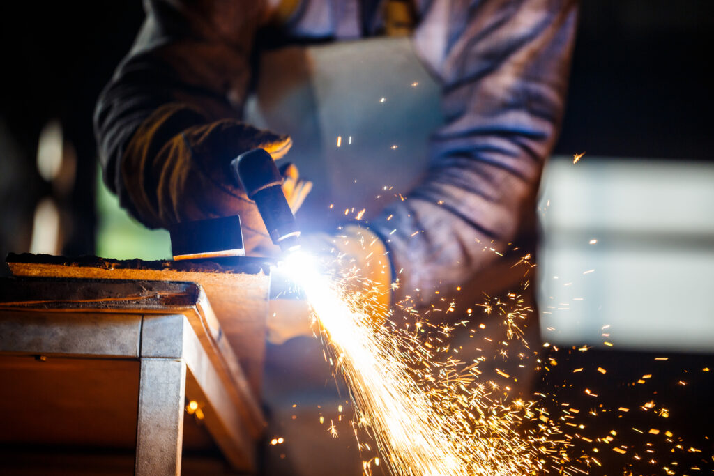 Trabalhador cortando metal com equipamento de plasma em uma planta de serralharia, Worker cutting metal with plasma equipment on a metalworking plant, Travailleur coupant du métal avec un équipement plasma dans une usine de métallerie, Pracownik tnący metal za pomocą sprzętu plazmowego w zakładzie ślusarskim.