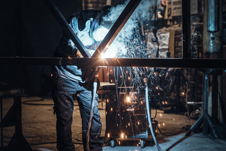 Trabalhador cortando metal com equipamento de plasma em uma planta de serralharia, Worker cutting metal with plasma equipment on a metalworking plant, Travailleur coupant du métal avec un équipement plasma dans une usine de métallerie, Pracownik tnący metal za pomocą sprzętu plazmowego w zakładzie ślusarskim. Ślusarstwo